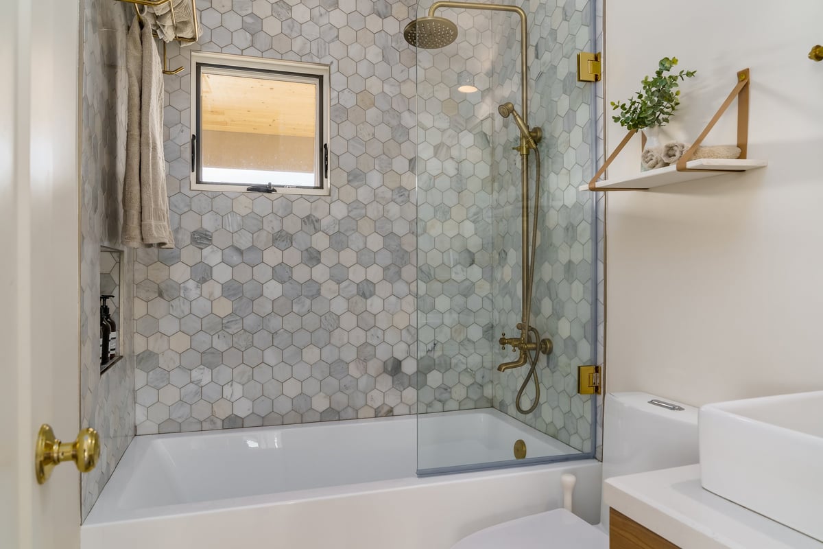 Modern white bathroom with a tiled walk-in shower and brass fixtures